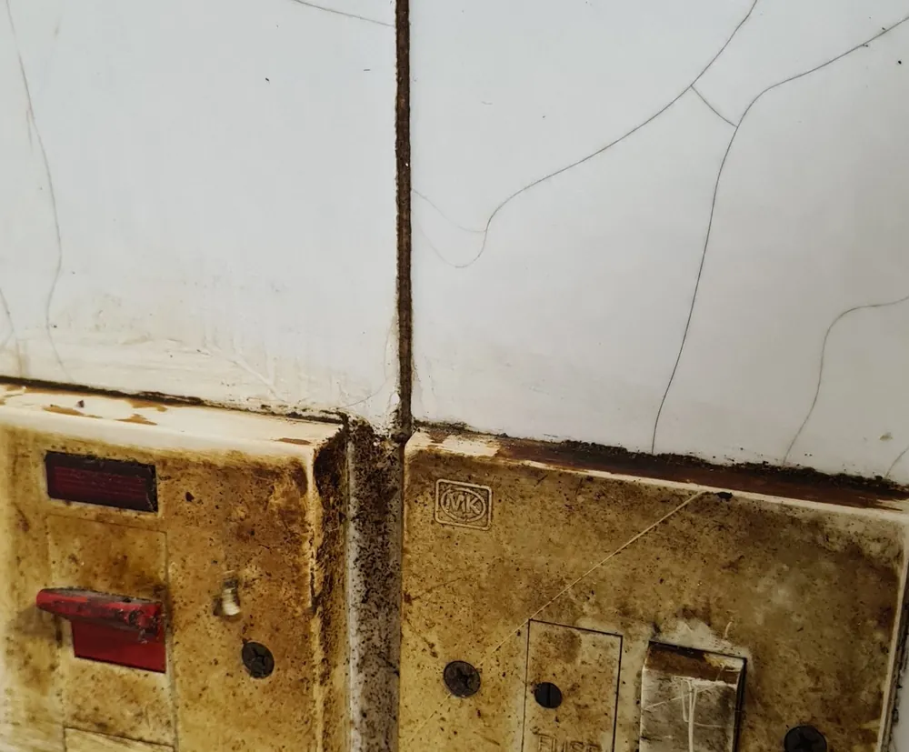 Before deep cleaning: wall switches and tiles covered in grime and mould