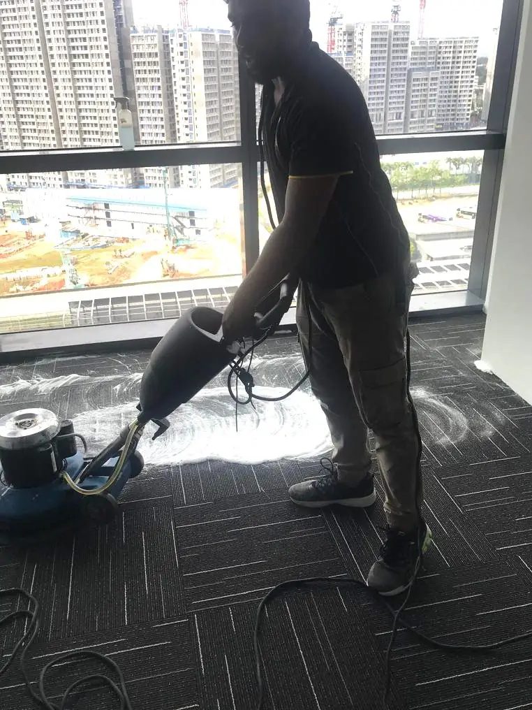 Imperial Services cleaner operating a carpet cleaning machine on commercial carpet in Singapore